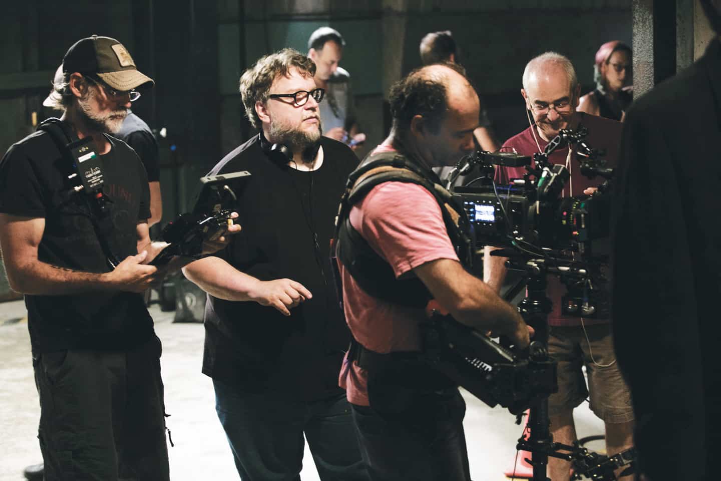 Photograph of Guillermo del Toro directing on a film set. There are 7 people visible, including a camera operator.